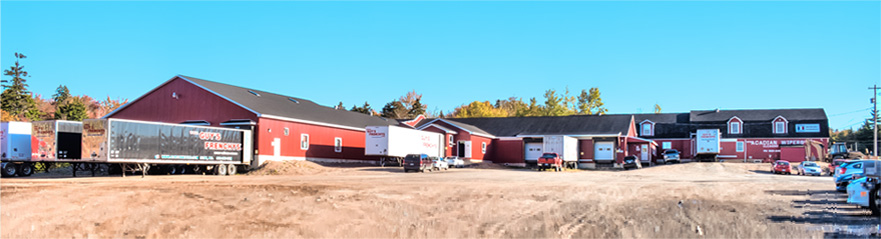 A long, red building with many transport trucks outside.